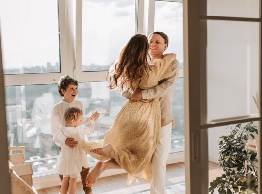 A joyful family embraces in a sunlit modern apartment, celebrating togetherness and love.