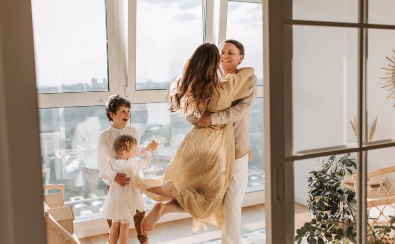A joyful family embraces in a sunlit modern apartment, celebrating togetherness and love.